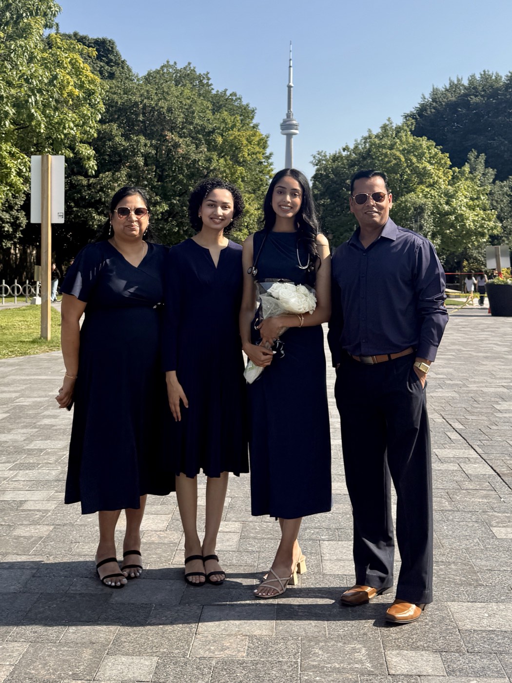 Left to right: Ruby, Prachi, Pankhudi and Arvind Choudhary standing together outdoors in Toronto, the CN Tower rising behind them.